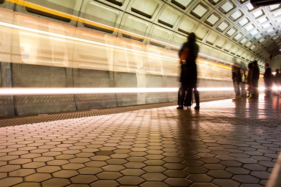 Washington DC Metro subway platform with passengers waiting and blurred train passing.